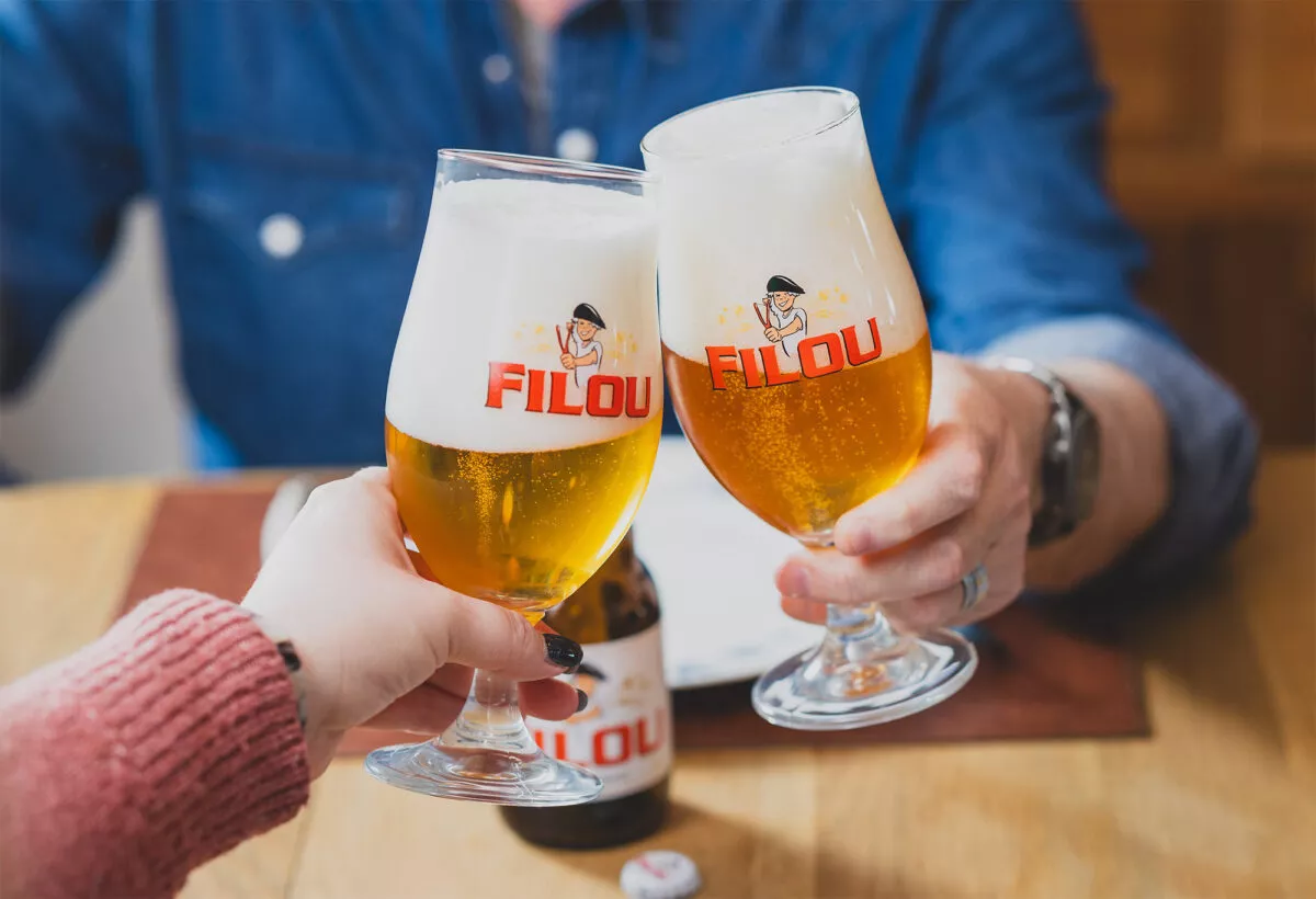 Twee mensen proosten met Filou bier in een glas – Filou is een Belgisch bier van Kasteel Brouwerij Vanhonsebrouck.
