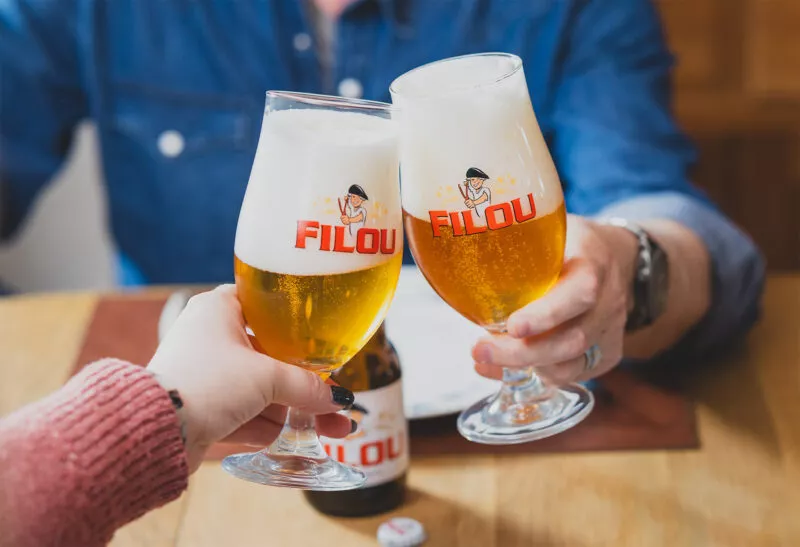 Twee mensen proosten met Filou bier in een glas – Belgisch bier van Filou brouwerij.