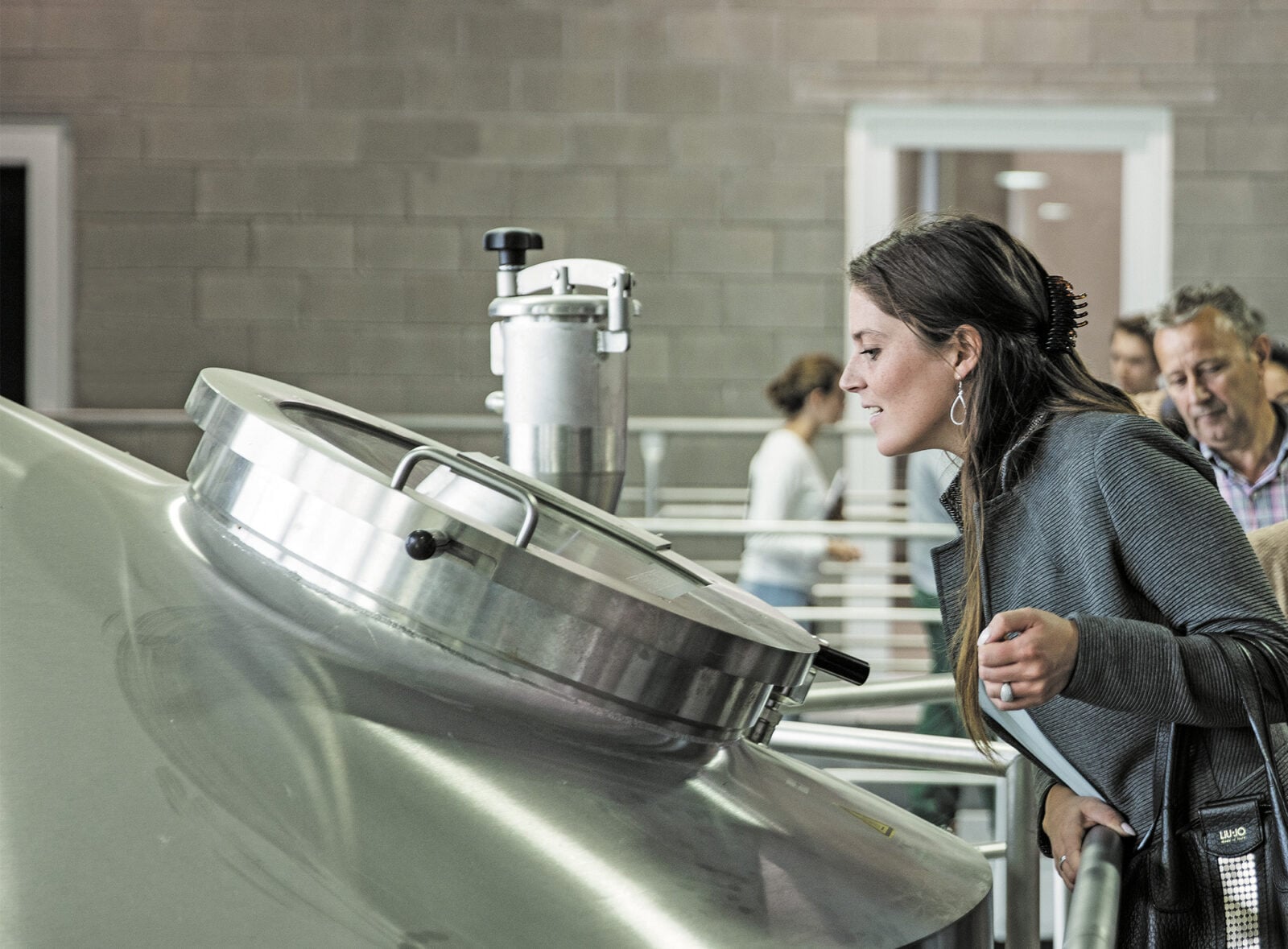 Een vrouwelijke bezoeker neemt een kijkje in een brouwketel tijdens een rondleiding bij Kasteel Brouwerij Vanhonsebrouck, de modernste brouwerij van Europa gelegen in Izegem en dagelijks te bezoeken met gids.
