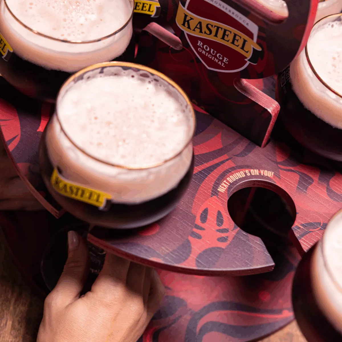 Kasteel Rouge at the Campus - Handen nemen glazen Kasteel Rouge uit iets wat een roulette lijkt. 